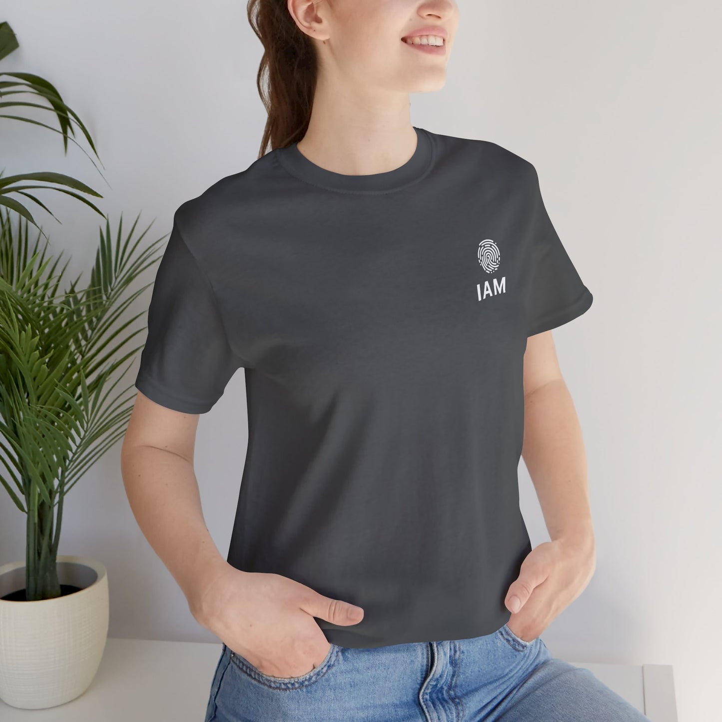 Person wearing a asphalt t-shirt with 'IAM' logo in a minimal indoor setting