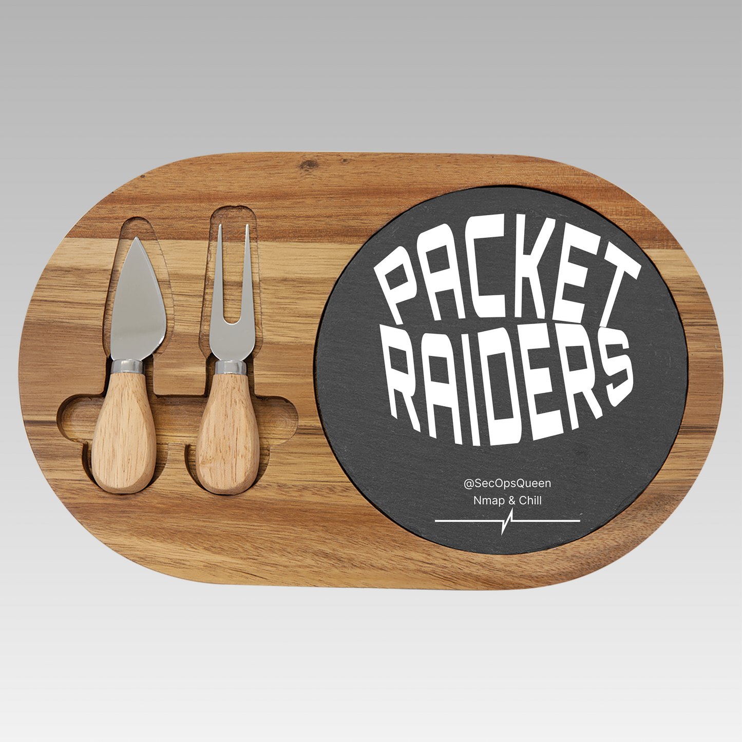Oblong Wooden charcuterie board with 'Packet Raiders' sign and cheese tools on a gray background