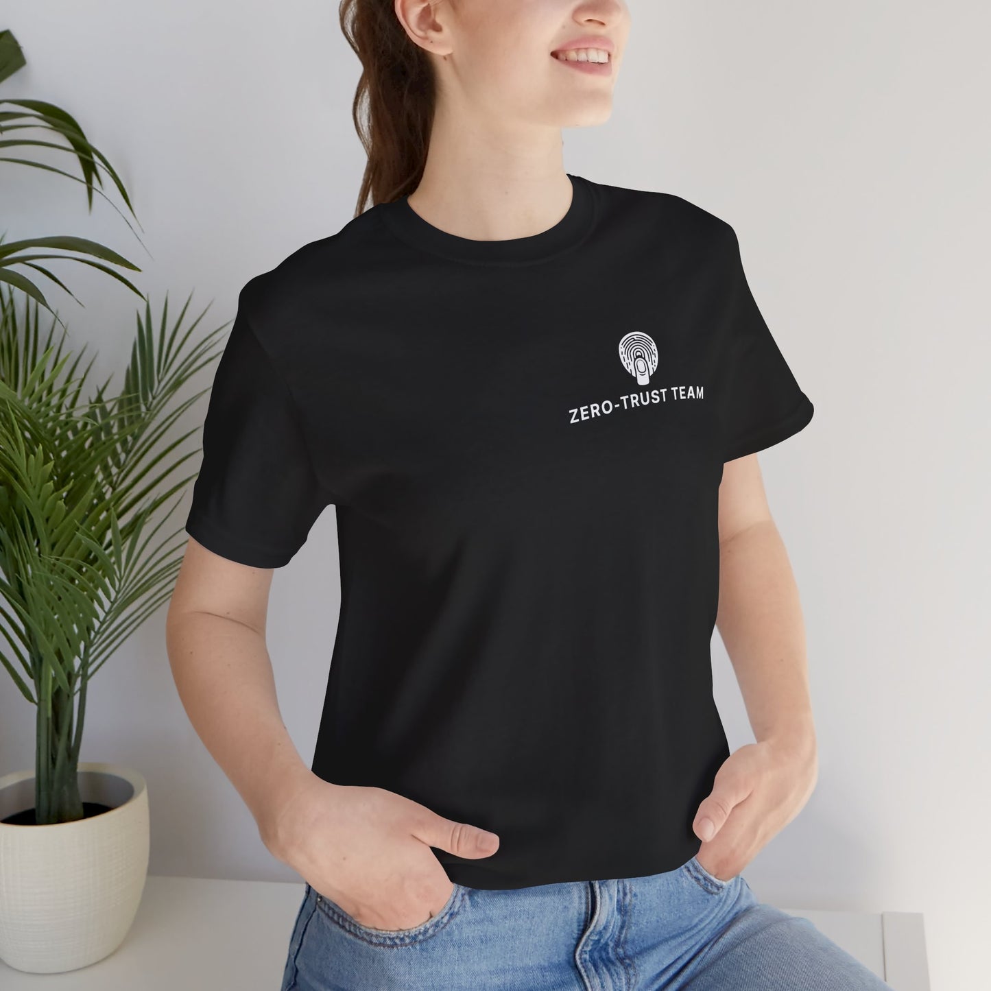 Person wearing a black t-shirt with 'ZERO-TRUST TEAM' text and logo, standing indoors.
