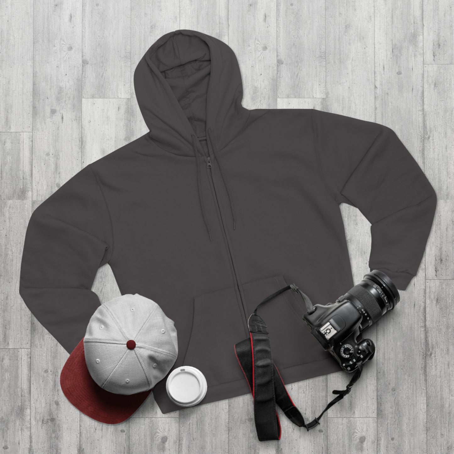 Dark gray hoodie with a cap, camera, and other items on a wooden surface