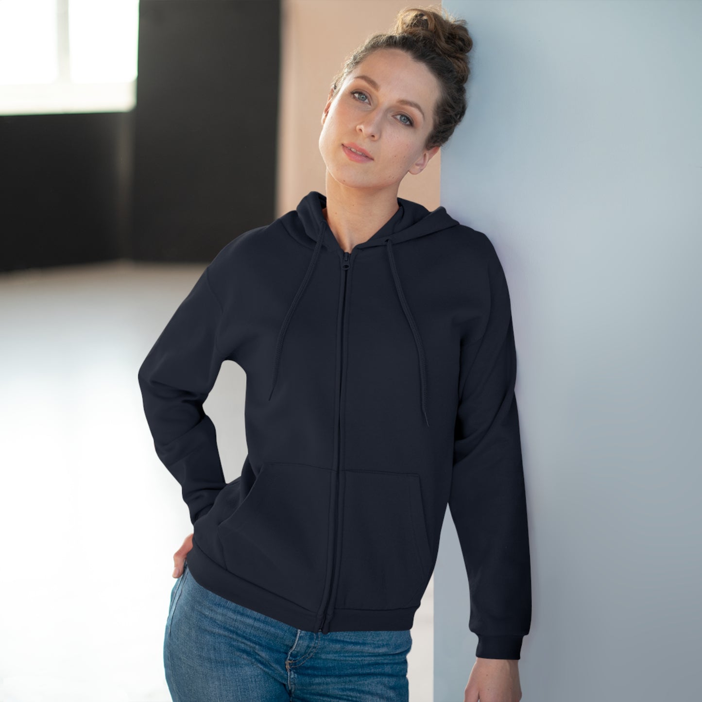 Woman wearing a Navy hoodie and blue jeans against a neutral background