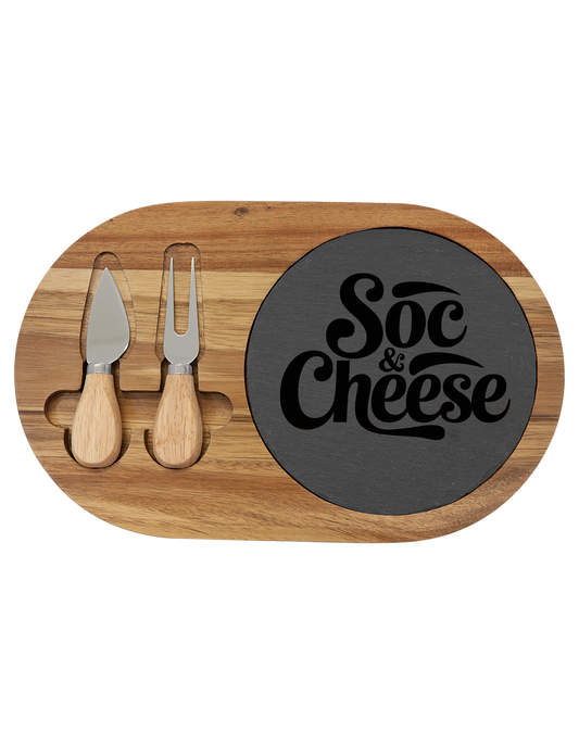 Wooden cheese board with two knives and a black slate.